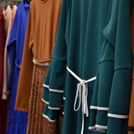 Langärmeliges Kleid mit Gürtel und weißen Verzierungen.