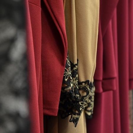 Weiche Stoffe in Rot und Beige mit bestickten Ärmeln.