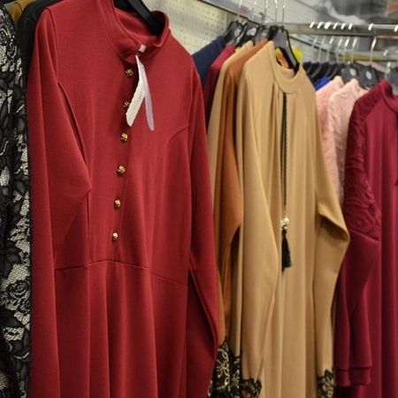 Elegantes langes Kleid mit Stehkragen, daneben beige und rote Kleider.