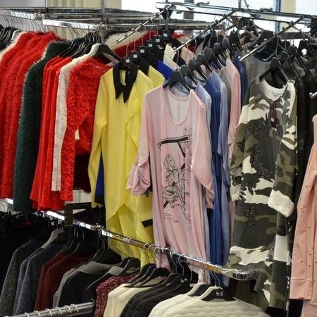 Verschiedene Oberteile auf Kleiderständern.