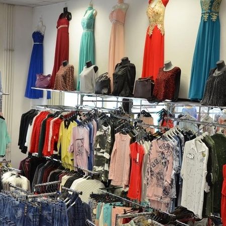 Bunte Kleidung auf Ständern – Blusen und Hosen im Geschäft.